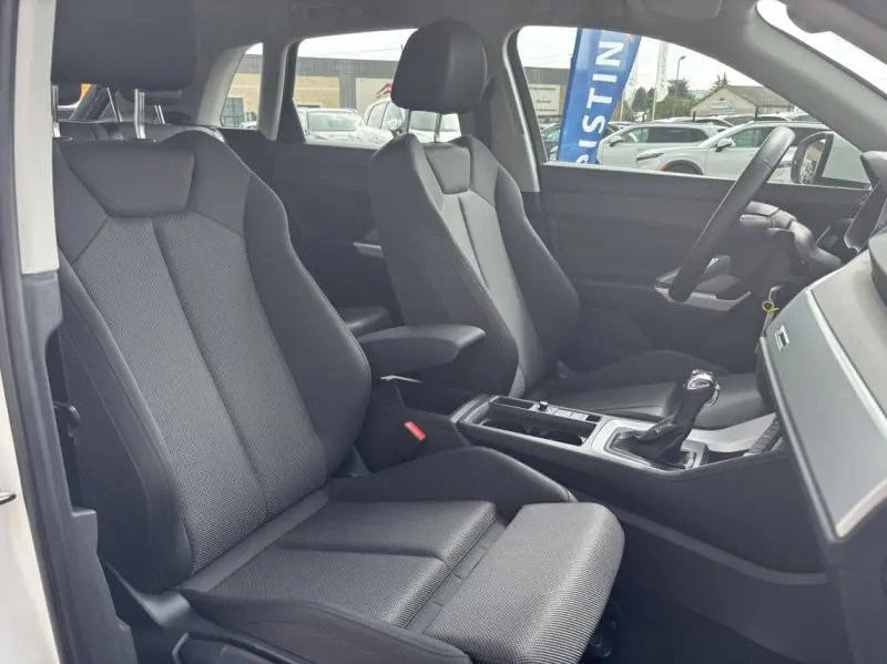 Vue intérieure côté conducteur de l'Audi Q3 35 TFSI 2022 avec sièges sport noirs et console centrale moderne.