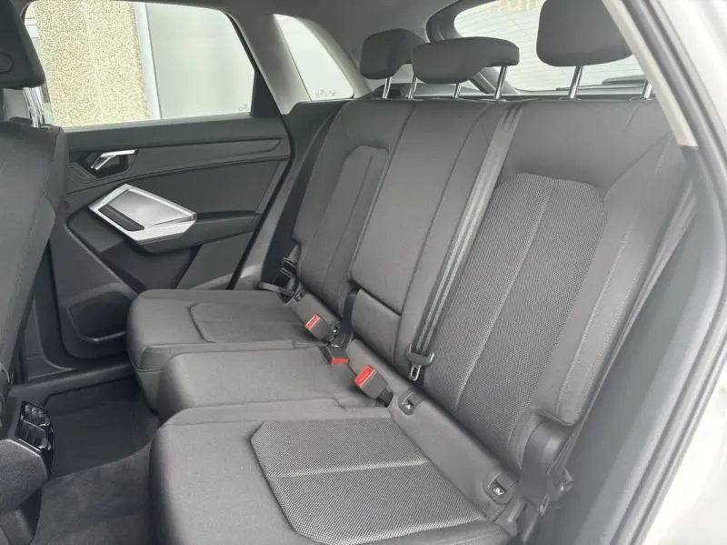 Vue latérale intérieure du siège arrière en tissu gris foncé de l'Audi Q3 blanc Glacier 2022.