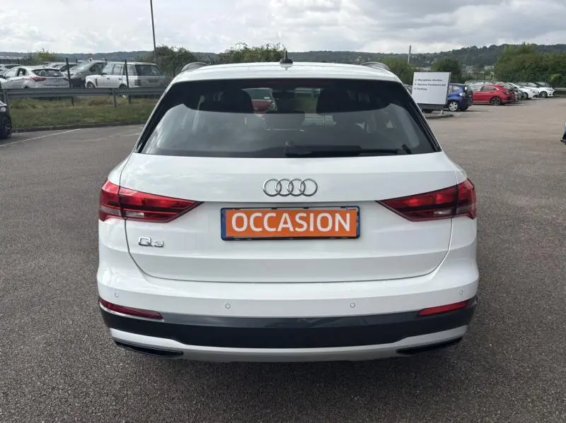 Vue arrière d'un Audi Q3 blanc Glacier métallisé avec plaque "OCCASION" sur un parking extérieur.