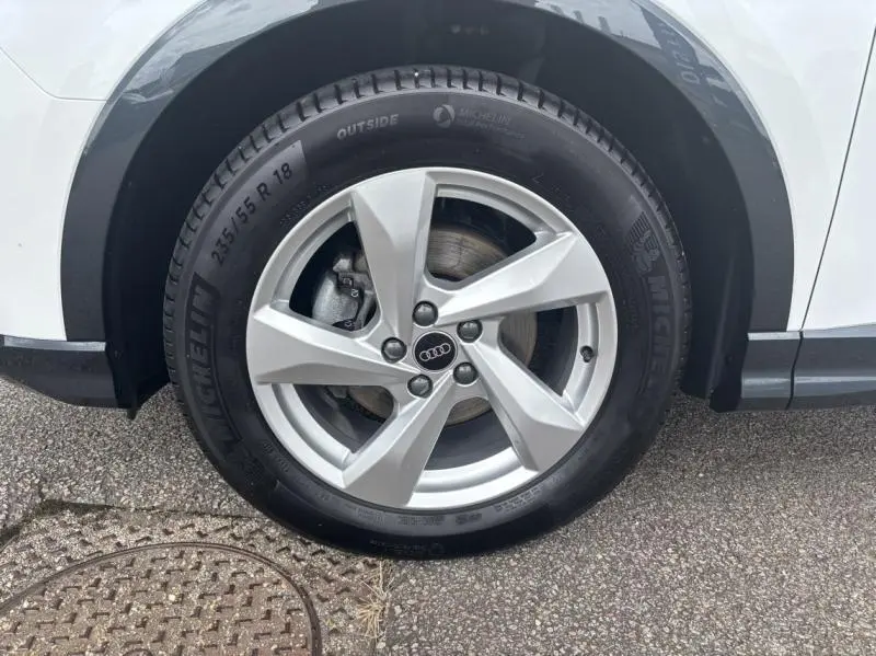 Gros plan sur la roue avant droite avec jante alu 5 branches de l'Audi Q3 blanc Glacier métallisé.