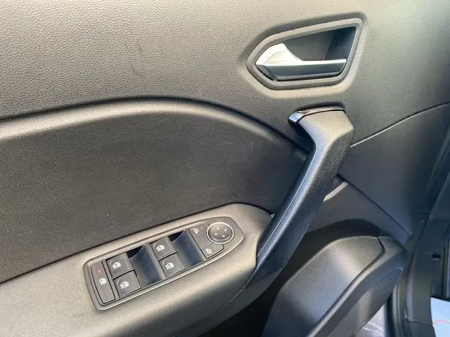 Gros plan sur la porte avant gauche du Renault Captur gris Cassiopée 2023, montrant les commandes des vitres et la poignée noire.
