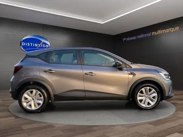 Renault Captur TCE 90 Équilibre gris Cassiopée vu de profil côté gauche, sur plateau en showroom moderne.