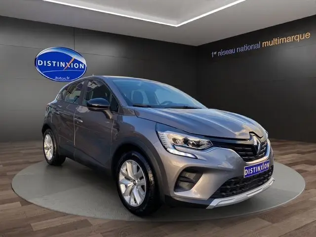 Renault Captur TCE 90 Équilibre gris Cassiopée en 3/4 avant droit, phare LED et calandre noire brillante visible.