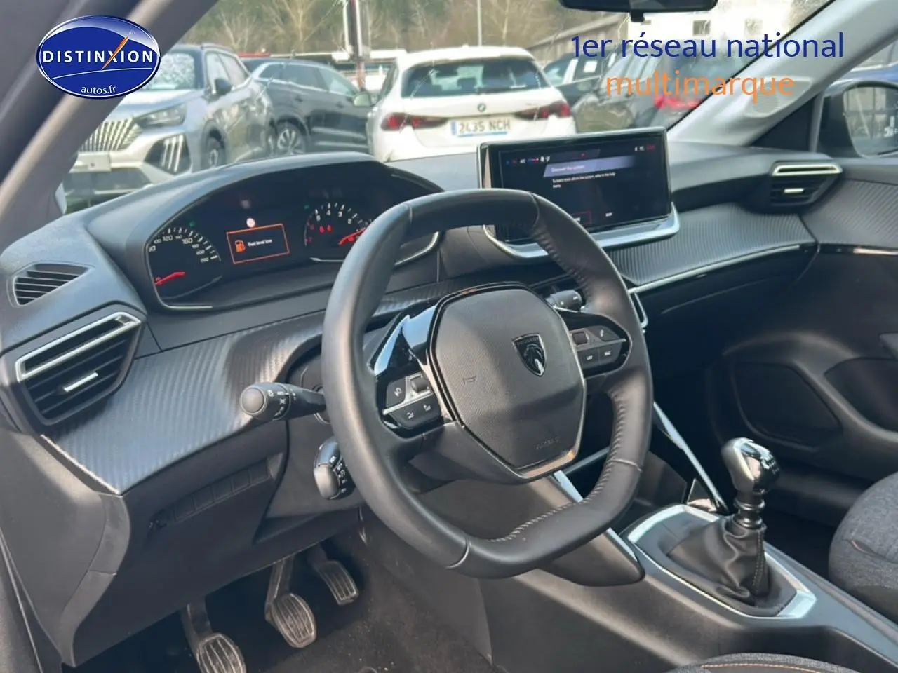 Intérieur de la Peugeot 208 1.2 100 Style 2025, vue du poste de conduite avec volant cuir et boîte manuelle.