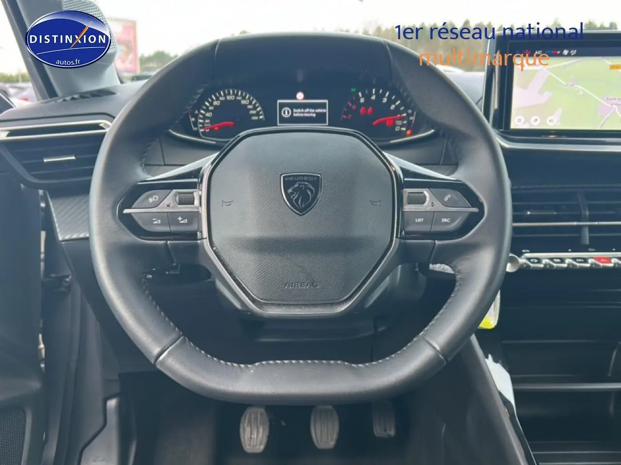 Vue intérieure centrée sur le volant Peugeot 208 1.2 100 style avec commandes intégrées et tableau de bord numérique.