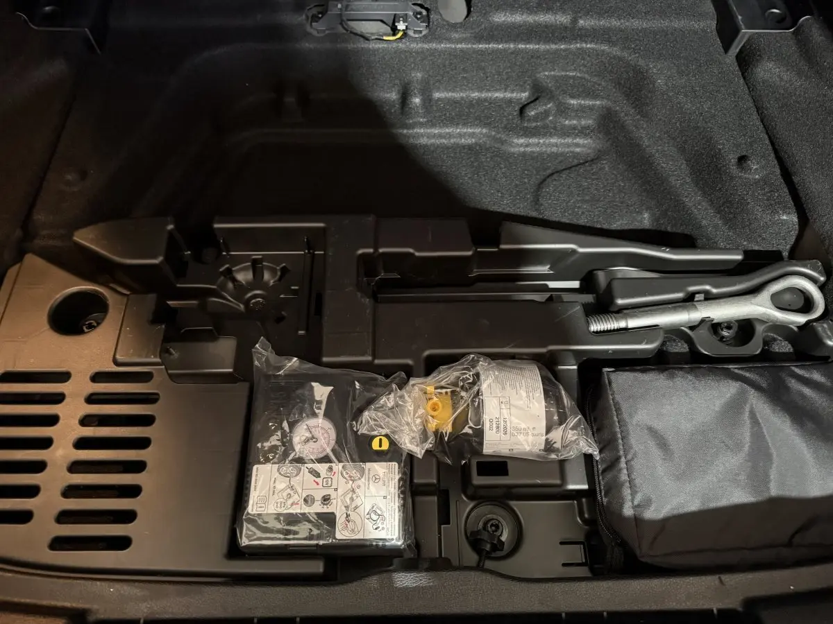 Vue rapprochée du coffre avec kit de réparation pneus et outils dans une Mercedes Classe A 200 AMG Line gris foncé 2021.
