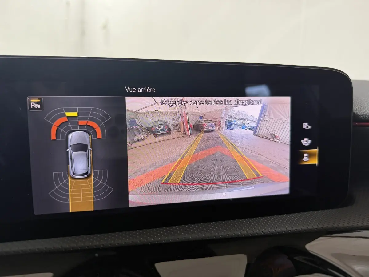 Écran multimédia de la Mercedes Classe A 200 AMG Line montrant la caméra de recul et l'aide au stationnement active.