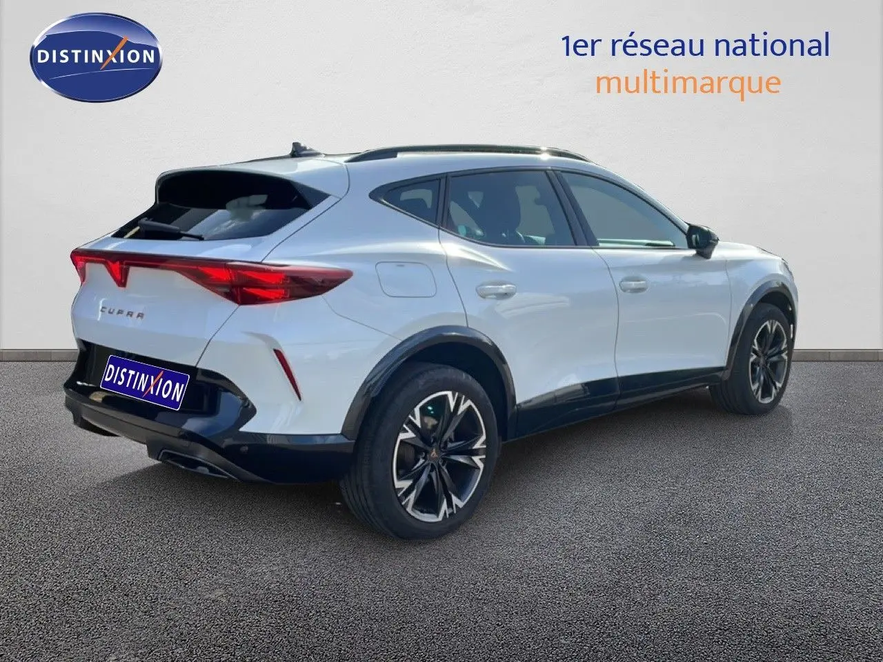 Vue 3/4 arrière droite d'un CUPRA Formentor blanc neige métal avec jantes noires bicolores et feux arrière LED distinctifs.