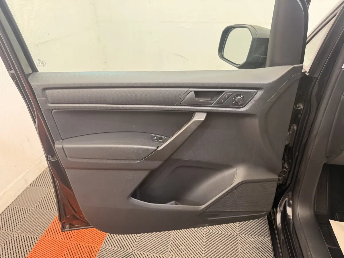 Vue intérieure de la porte avant gauche noire du Volkswagen Caddy 2019, avec commandes des vitres et rétroviseur.