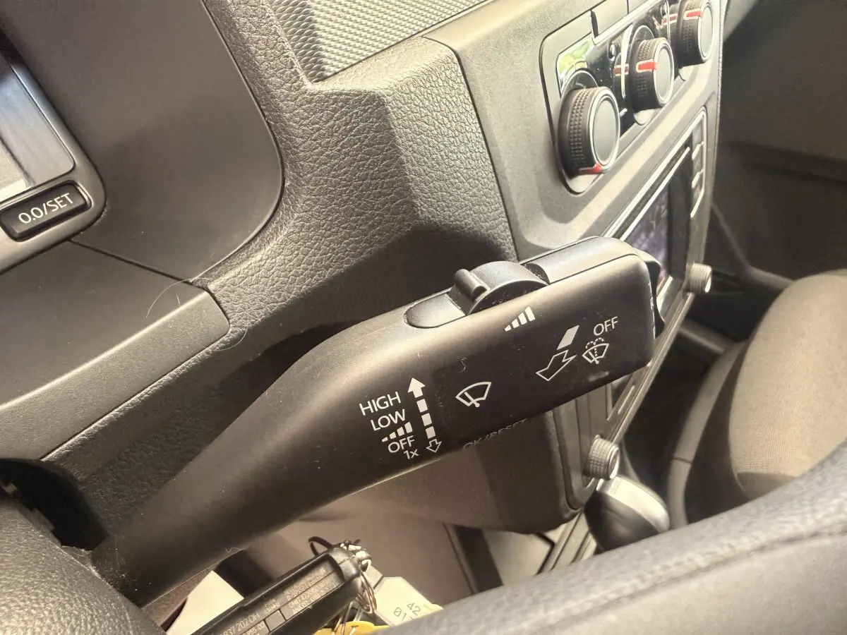 Gros plan sur la manette d’essuie-glace noire dans l’habitacle du Volkswagen Caddy 2019, avec tableau de bord gris.