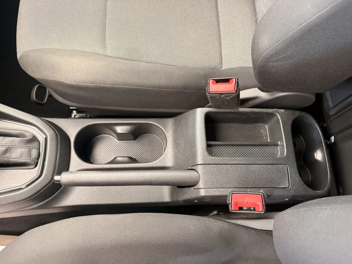 Vue plongeante sur la console centrale noire du Volkswagen Caddy 2019 avec levier de vitesse et porte-gobelets.
