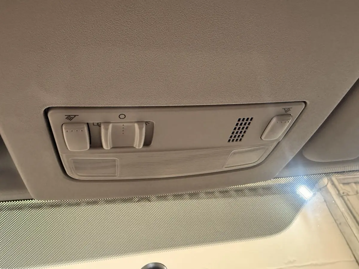 Plafonnier intérieur beige avec commandes d’éclairage et ventilation, vue depuis l’habitacle avant du Volkswagen Caddy noir.