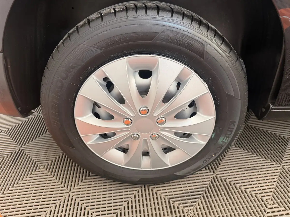 Gros plan sur la roue avant droite du Volkswagen Caddy noir, avec jante acier et enjoliveur argenté.