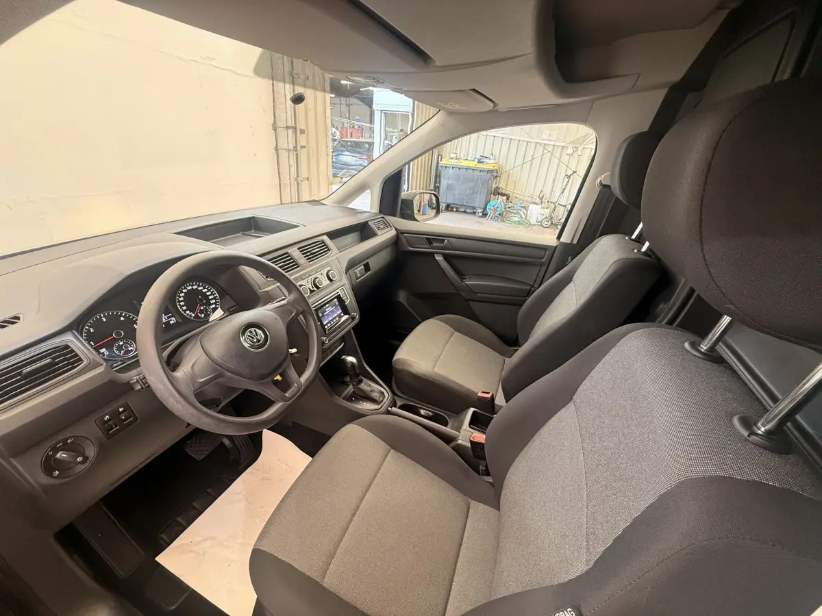 Vue intérieure avant droite du Volkswagen Caddy 2019 avec sièges gris et tableau de bord noir.
