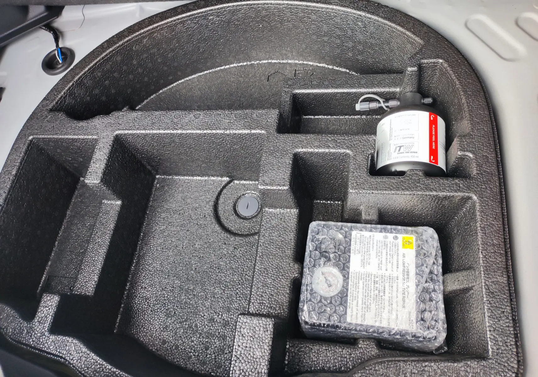 Rangement en mousse noire dans le coffre de la Mazda2 Hybrid 2024, avec kit de réparation pneus visible.