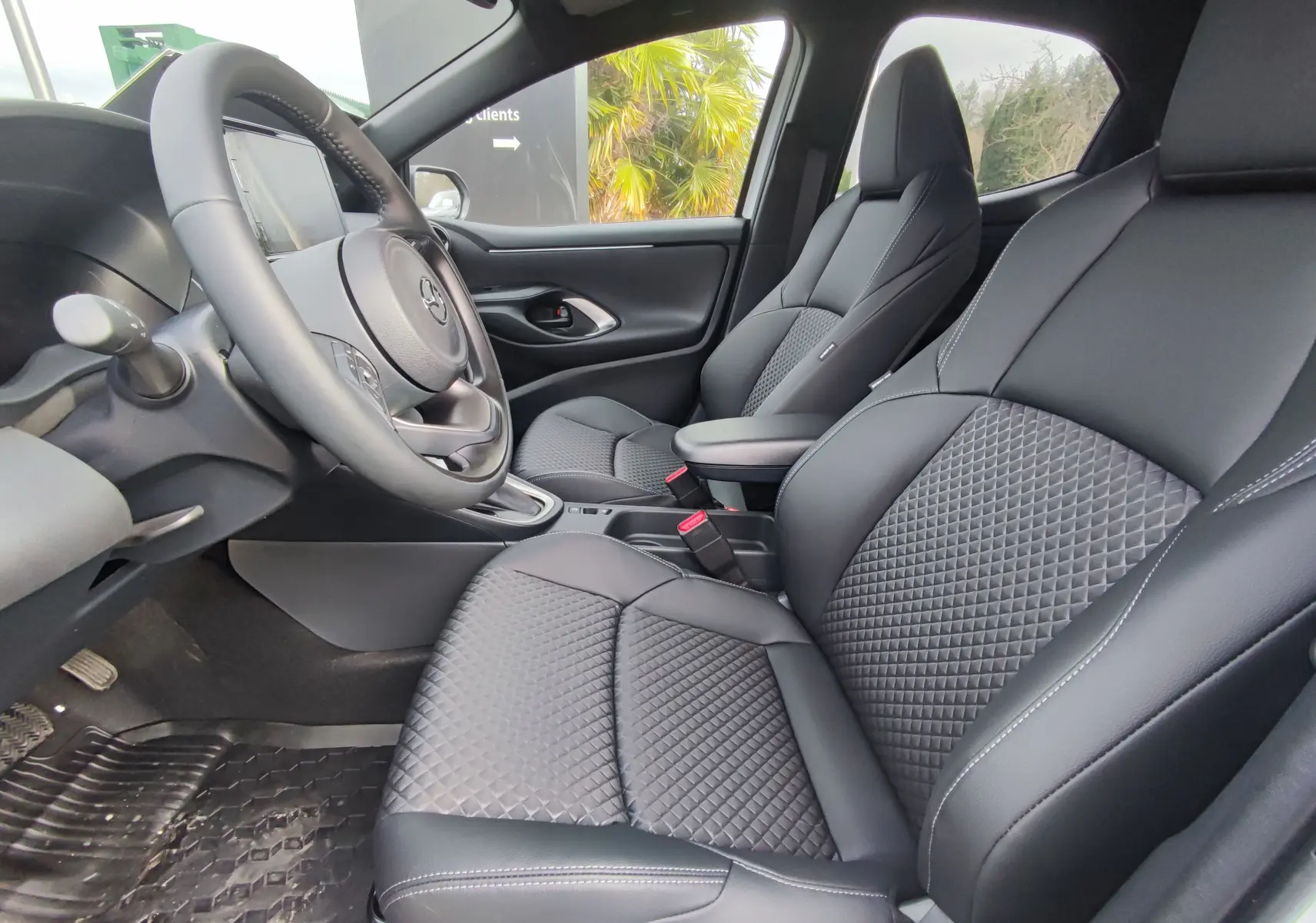 Vue intérieure côté conducteur de la Mazda2 Hybrid 2024 avec sièges en cuir noir matelassé et volant multifonction.