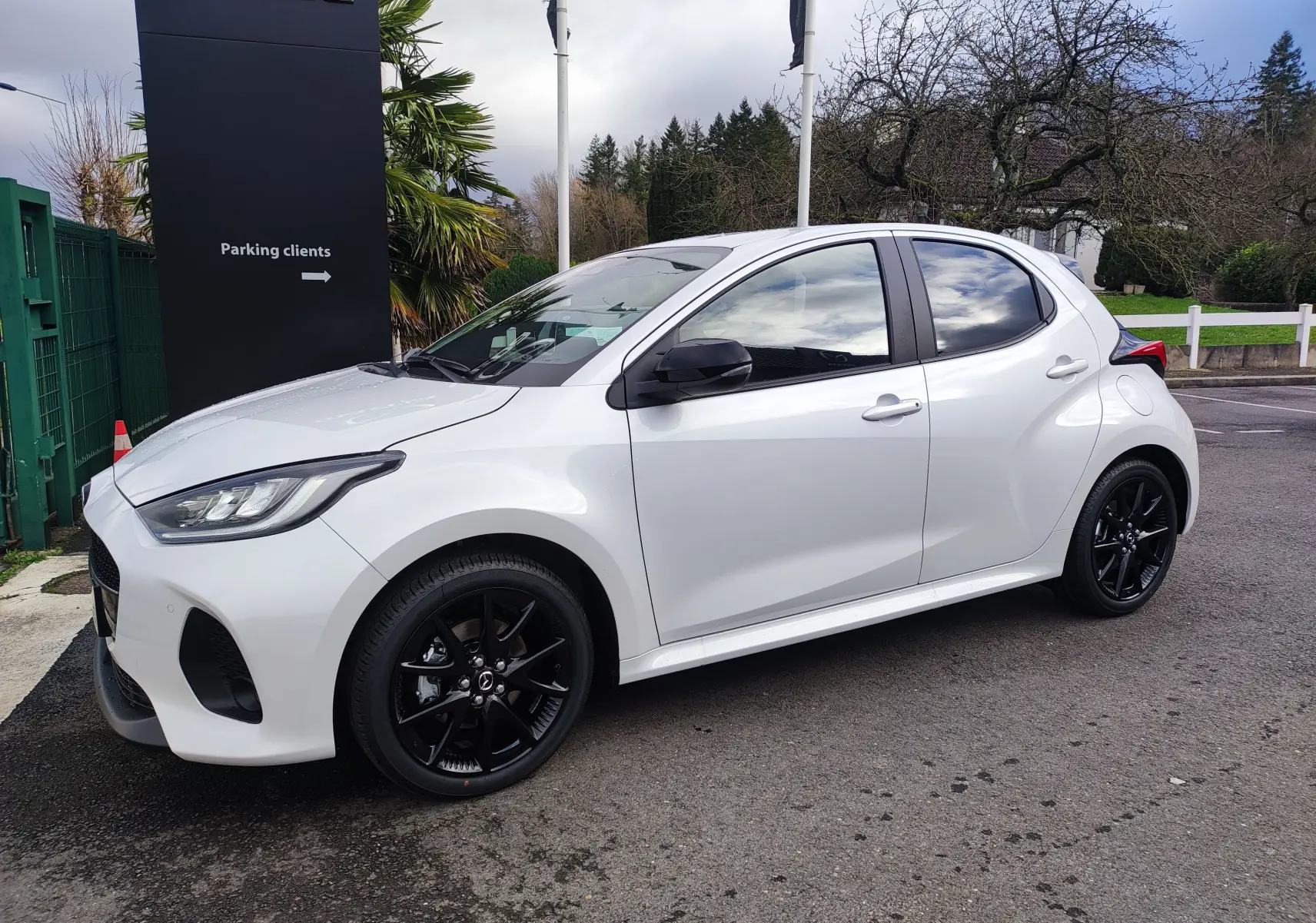 Vue de profil côté gauche d'une Mazda2 Hybrid 2024 blanc métallisé avec jantes noires et rétroviseurs noirs.