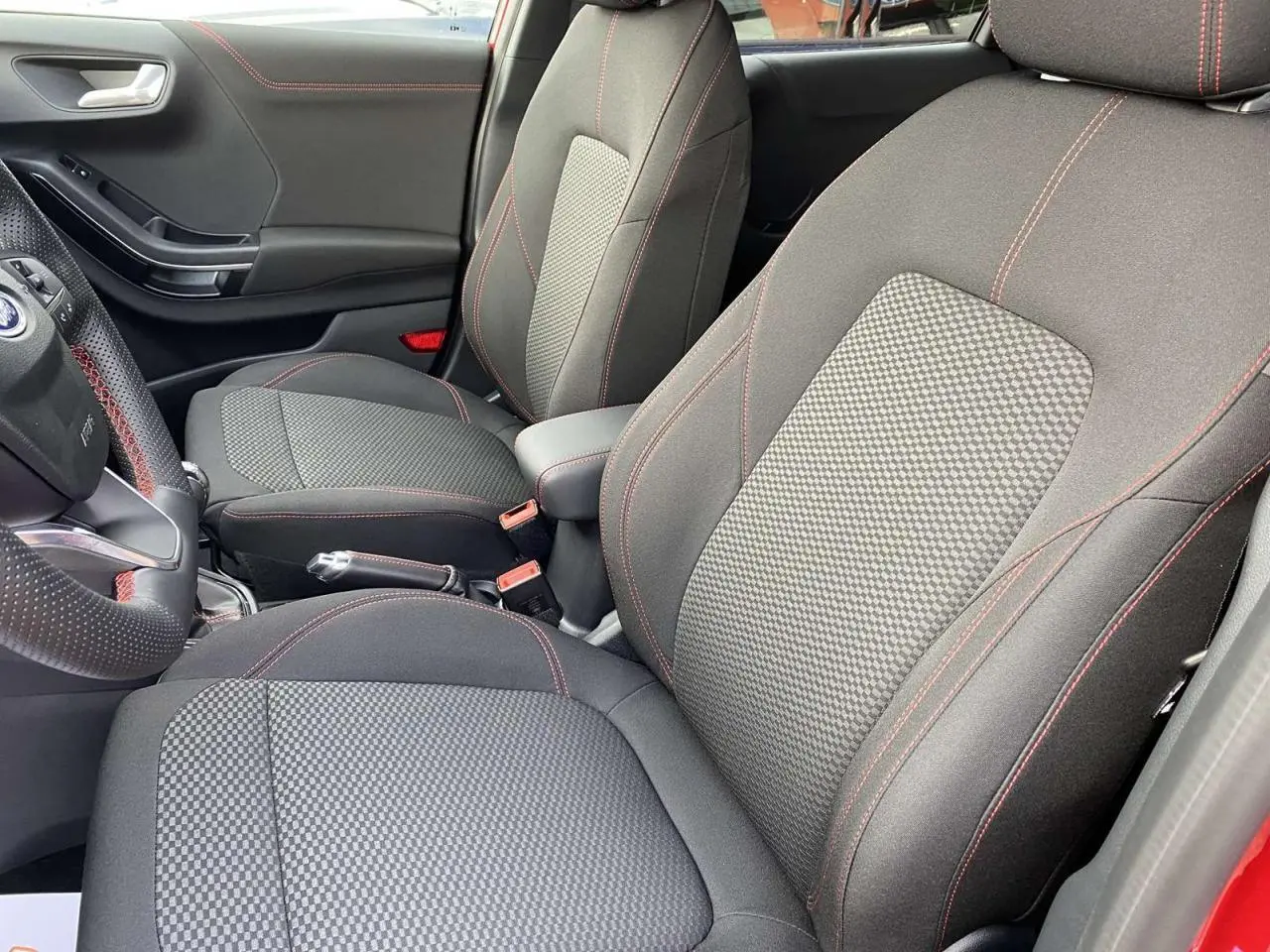 Vue intérieure côté conducteur du Ford Puma ST-Line 2022 avec sièges tissu gris à surpiqûres rouges et porte rouge Fantastic.
