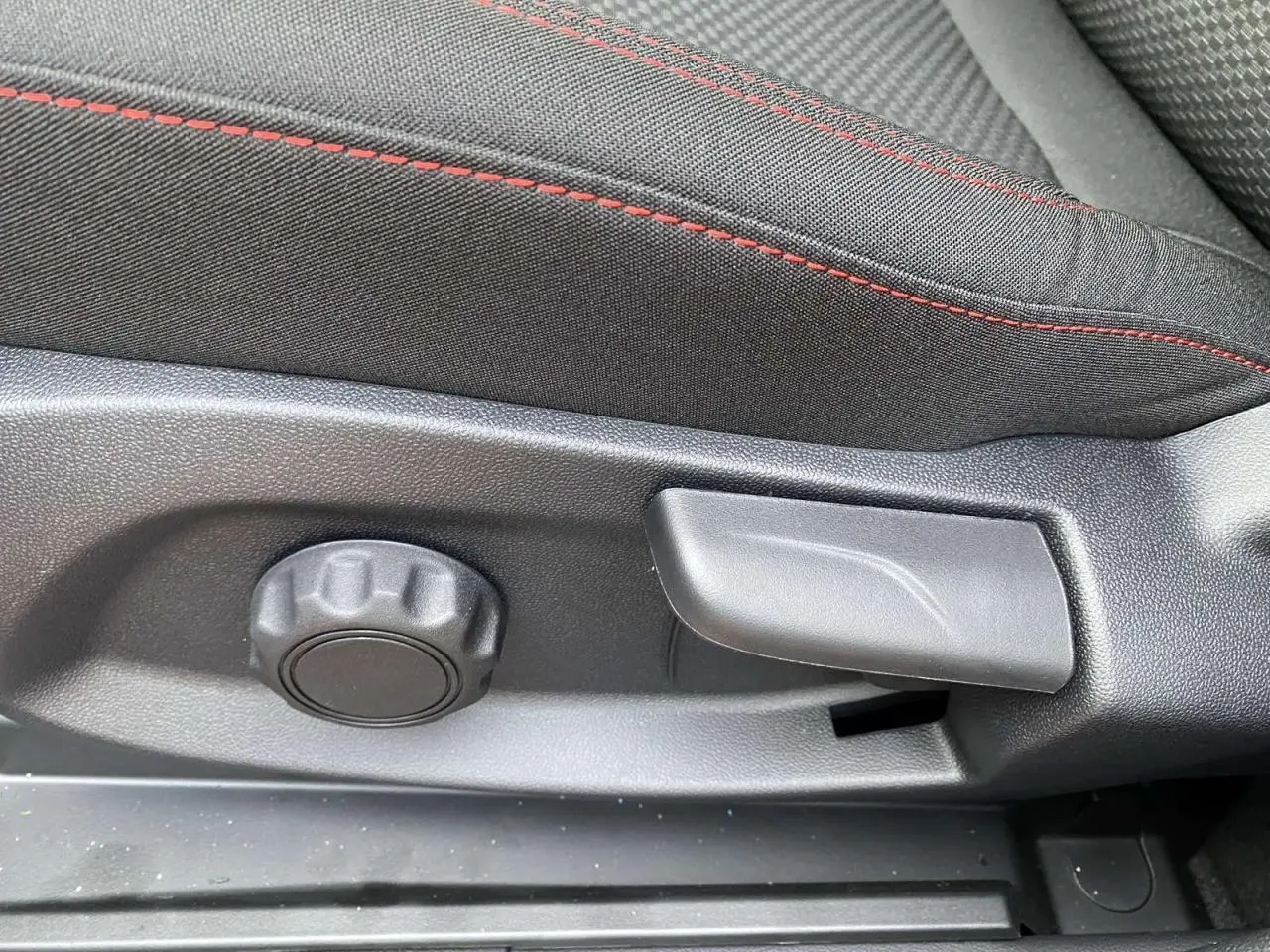 Réglage manuel du siège avant avec tissu noir et surpiqûres rouges dans un Ford Puma Rouge Fantastic 2022.