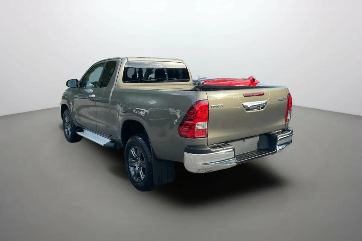 Toyota Hilux 4x4 2025 en bronze impérial, vue 3/4 arrière droit avec benne et jantes alliage visibles.