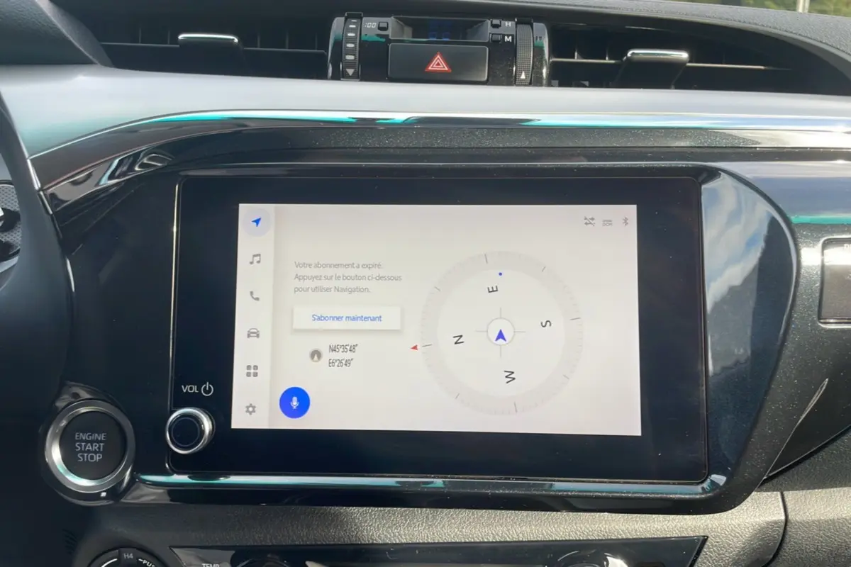 Écran tactile central du Toyota Hilux 2025 affichant une boussole, entouré de commandes noires brillantes.