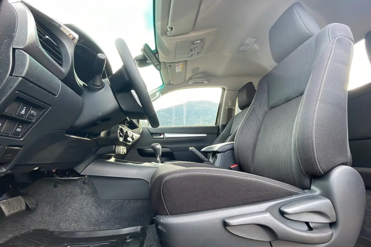 Intérieur du Toyota Hilux 4x4 2025 vu côté conducteur, sièges noirs et tableau de bord moderne.