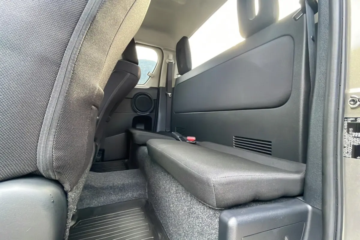 Vue intérieure arrière côté droit du Toyota Hilux 4x4 2025, avec banquette rabattue et garniture noire.
