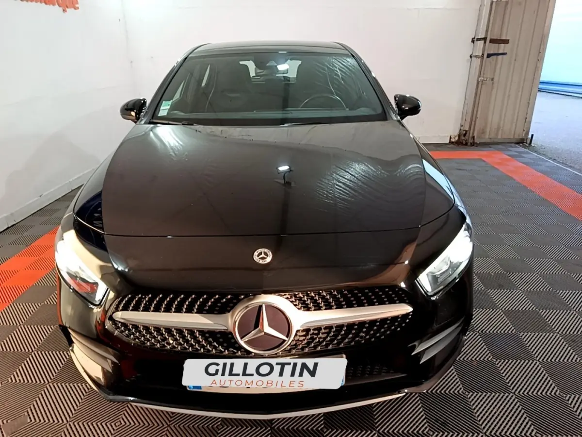 Vue avant d'une Mercedes Classe A 200 AMG Line noire avec calandre distinctive et phares LED allumés.