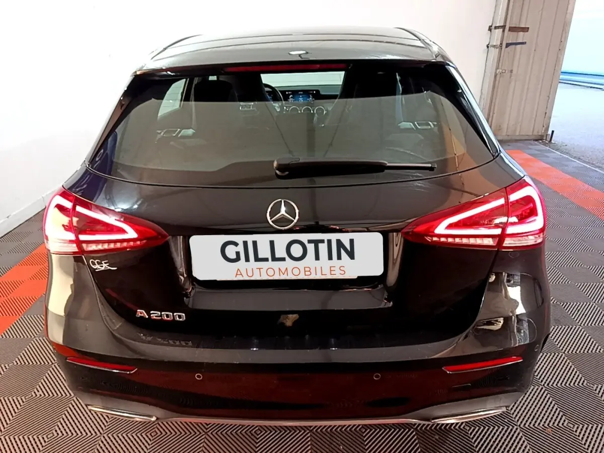 Vue arrière d'une Mercedes Classe A 200 AMG Line noire avec feux LED allumés dans un garage.