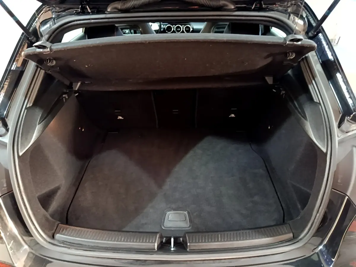 Coffre ouvert vu de l'arrière d'une Mercedes Classe A 200 AMG Line noire, montrant l'espace de chargement vide.