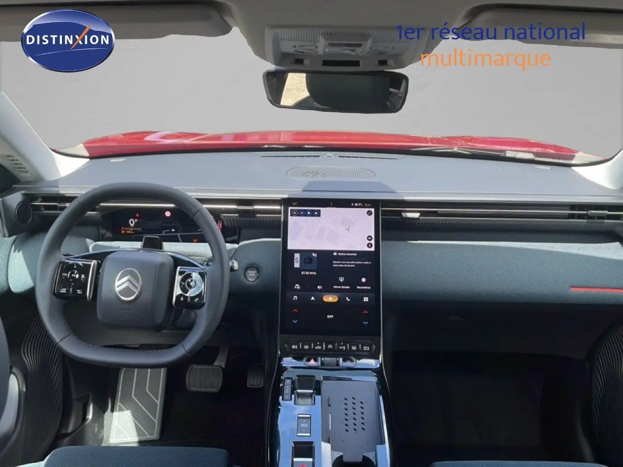 Vue intérieure frontale du tableau de bord du Citroën C5 Aircross Hybrid rouge rubis, avec écran tactile vertical et volant multifonction.