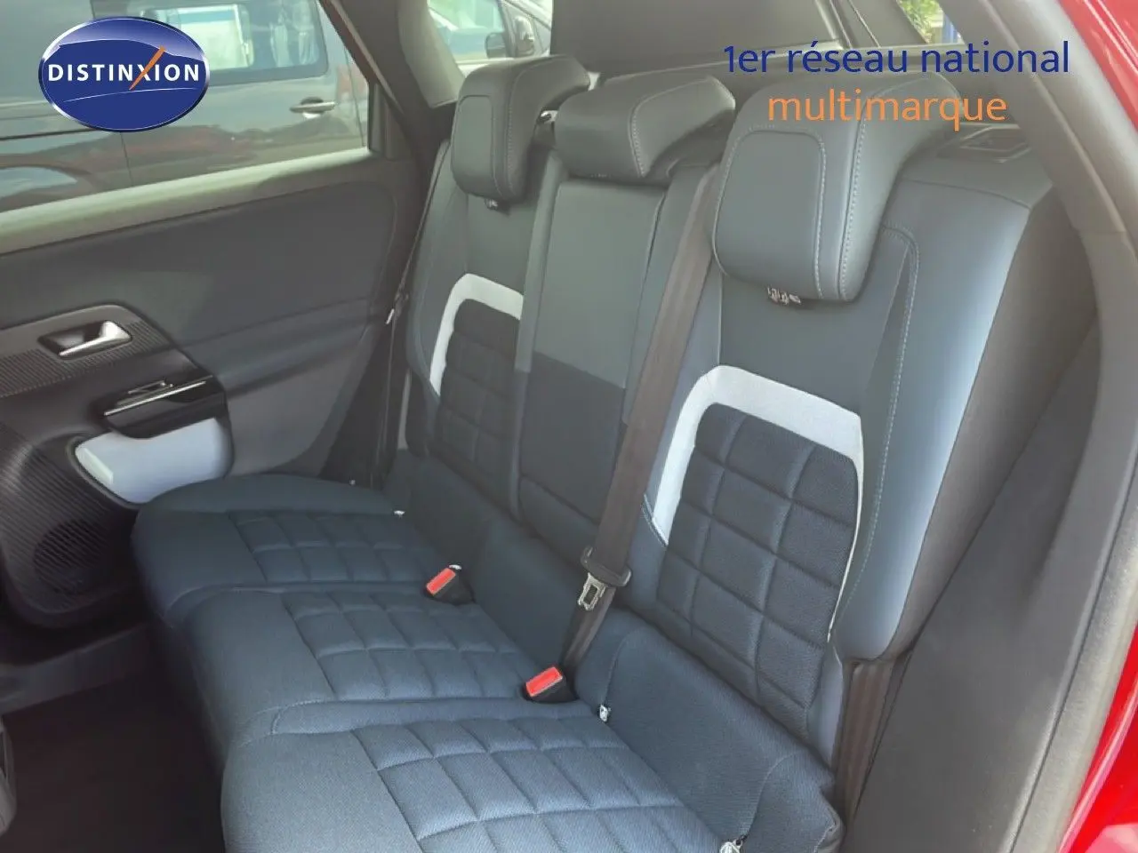 Vue intérieure côté arrière droit du Citroën C5 Aircross Hybrid rouge rubis, montrant les sièges arrière en tissu noir avec détails blancs.