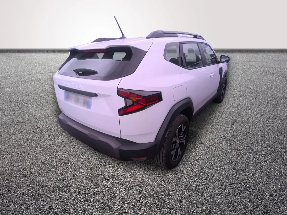 Vue 3/4 arrière droite d'un Dacia Duster blanc avec barres de toit noires et feux arrière LED distinctifs.