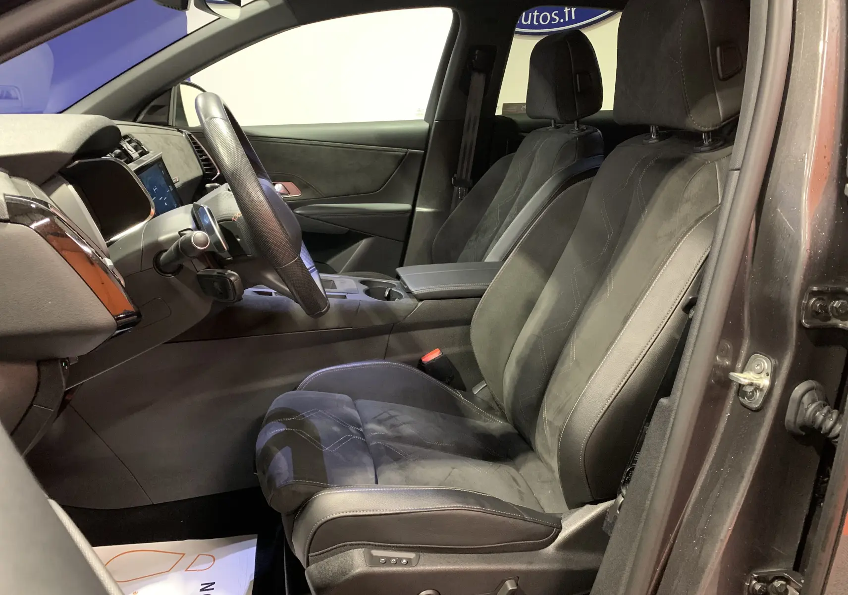 Intérieur côté conducteur du DS7 Crossback 2022 gris Platinium, sièges en cuir noir avec console centrale et volant visible.