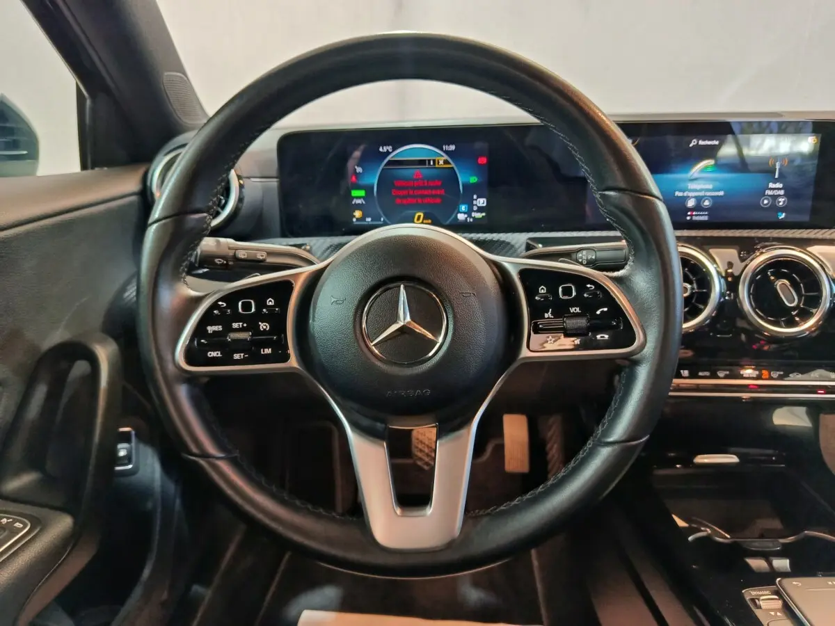Vue intérieure centrée sur le volant cuir noir d'une Mercedes Classe A 250 e avec tableau de bord digital.