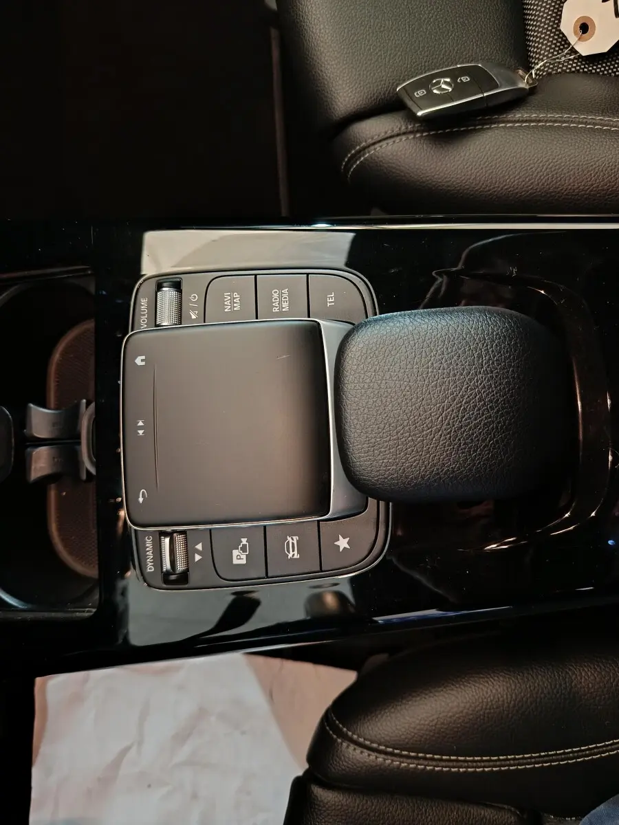 Vue plongeante sur la console centrale noire de la Mercedes Classe A 250 e avec pavé tactile et clé sur siège cuir noir.