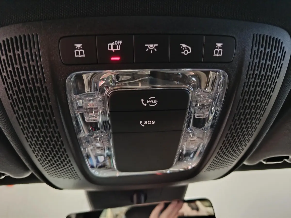 Vue intérieure en plongée sur la console de toit noire avec boutons SOS et éclairage de la Mercedes Classe A bleue.
