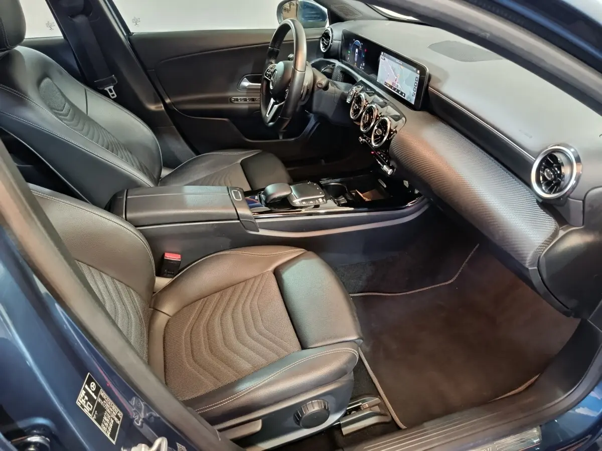 Vue intérieure côté conducteur de la Mercedes Classe A 250 e Business Line 2021 bleu, avec sièges cuir et écran tactile.