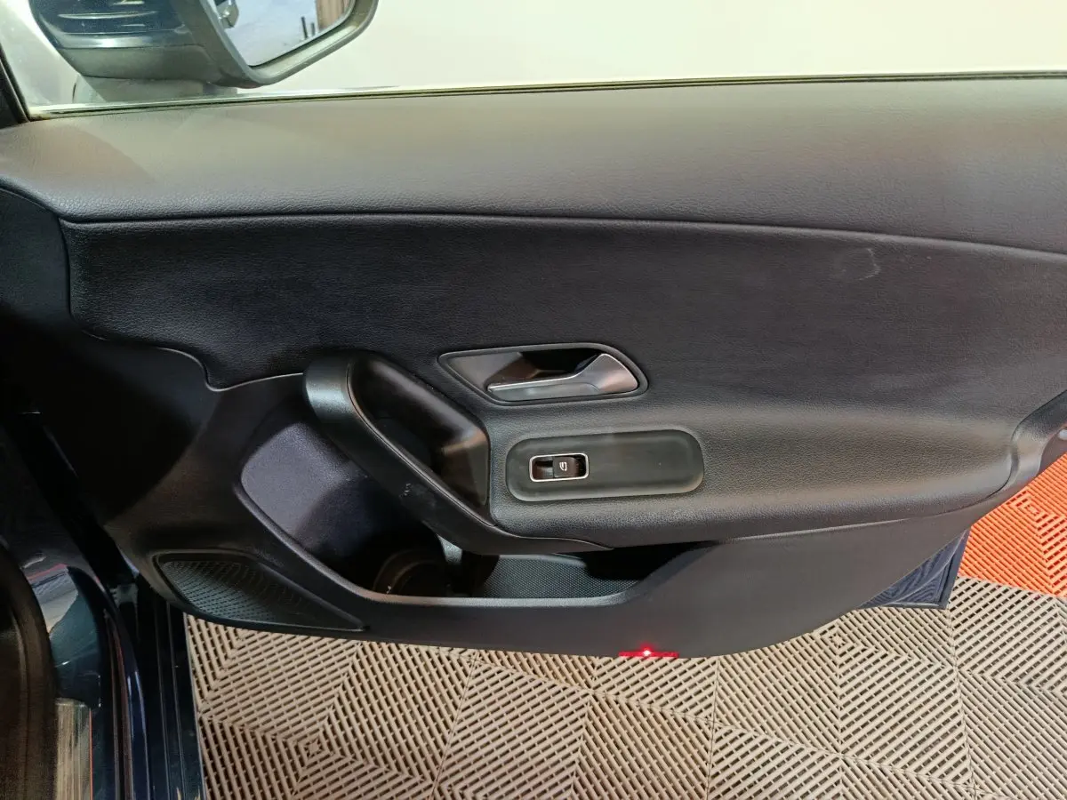 Vue intérieure côté gauche de la porte avant d'une Mercedes Classe A 250 e Business Line bleu avec commandes de fenêtre.