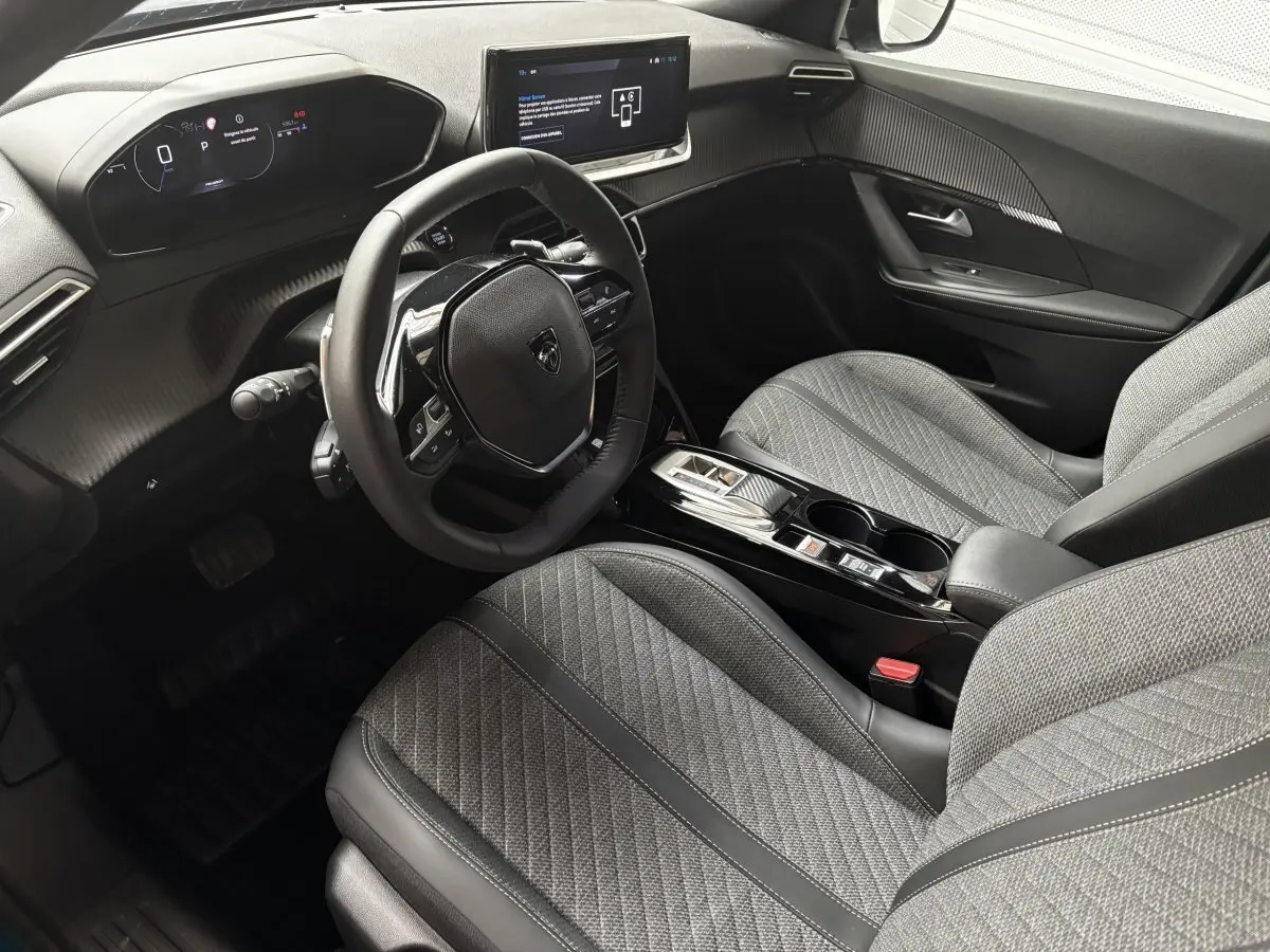 Vue intérieure côté conducteur du Peugeot 2008 Hybrid 145 e-DCS6 Allure 2025, sièges gris et tableau de bord digital.