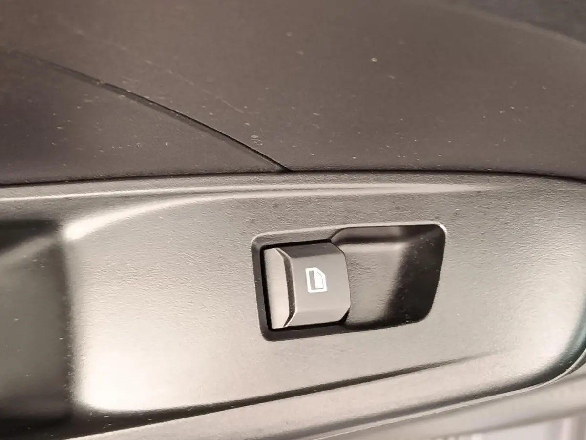 Gros plan sur le bouton de commande de vitre électrique noir dans l’habitacle d’une MG3 gris foncé 2024.