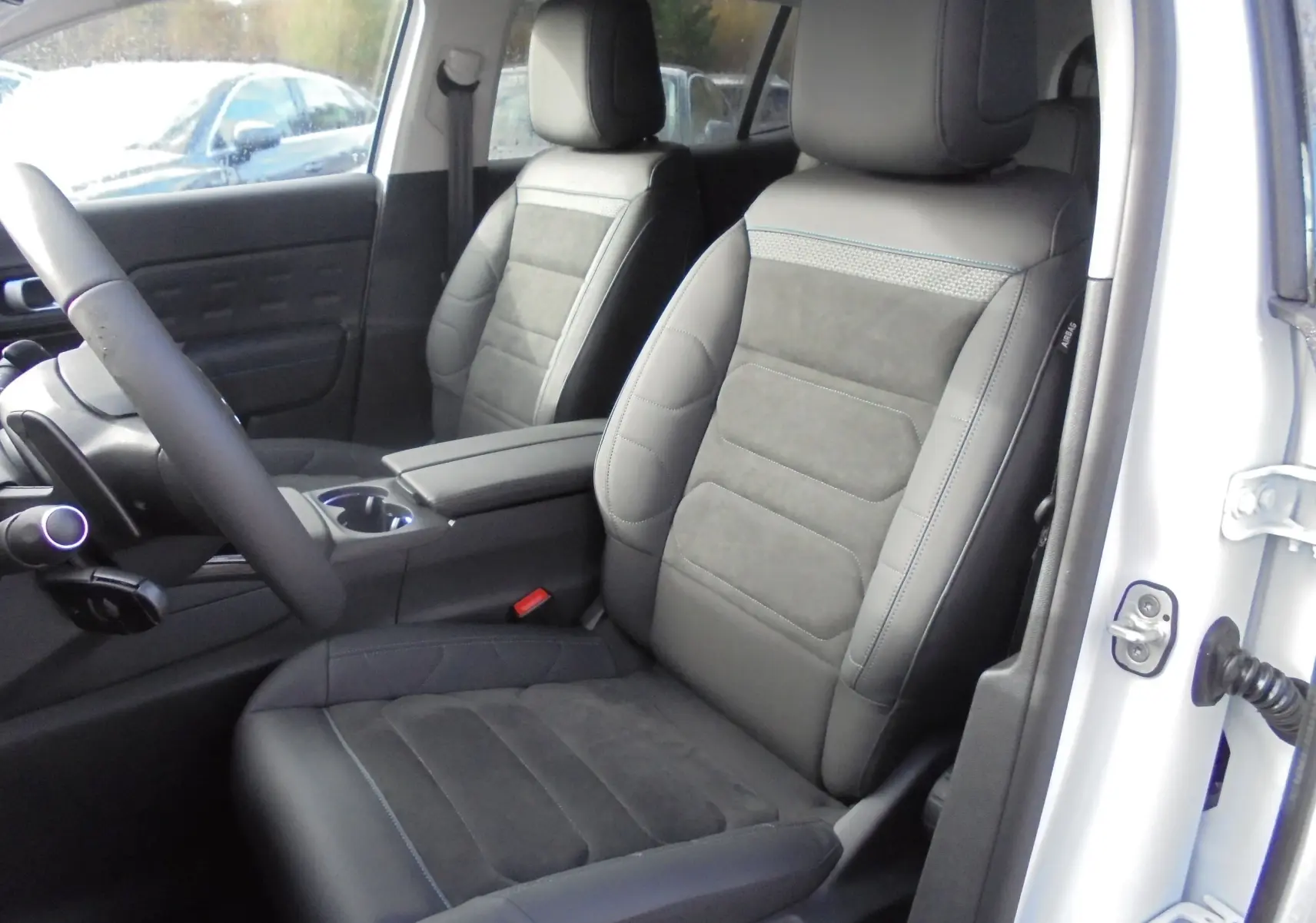 Vue intérieure côté conducteur du Citroën C5 Aircross 2022, sièges cuir noir avec surpiqûres bleues, portière blanche ouverte.