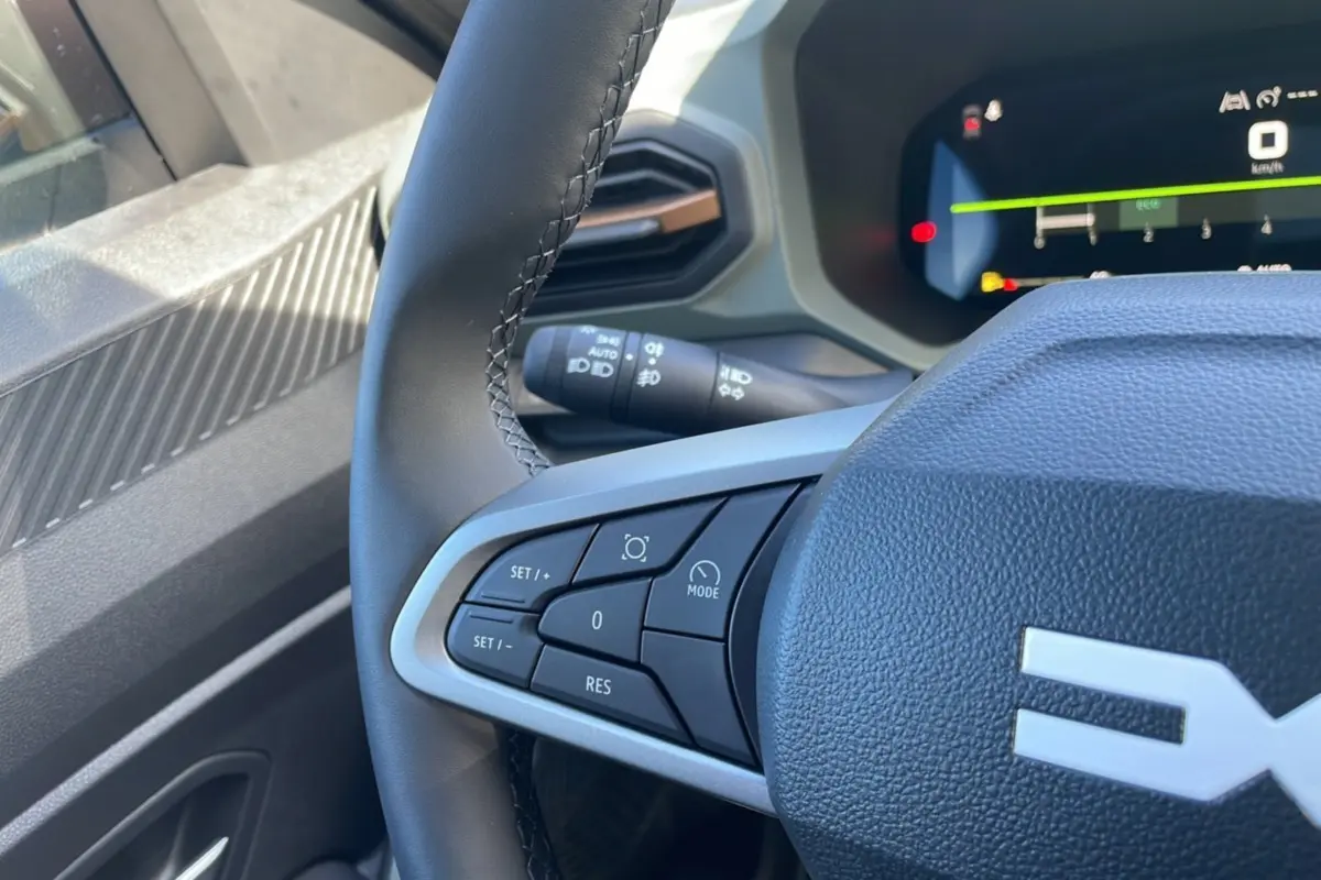Vue rapprochée du volant du Dacia Bigster 2025 gris schiste, montrant les commandes de régulateur de vitesse côté gauche.