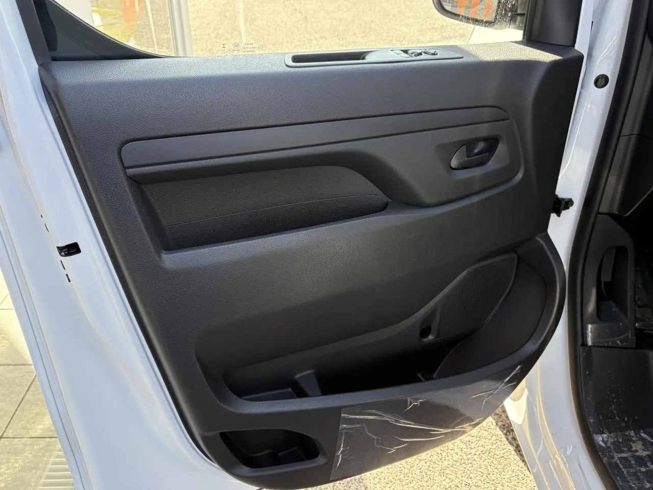 Vue rapprochée de la porte avant gauche blanche d’un Opel Vivaro 2024 avec panneau intérieur noir et poignée intégrée.