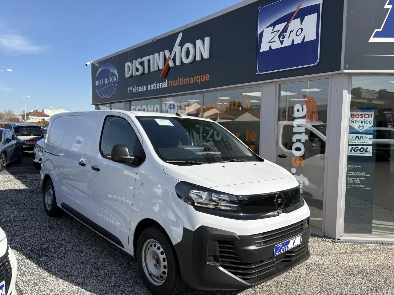 Opel Vivaro blanc vu en 3/4 avant droit, avec calandre noire et pare-chocs avant massif noir mat.