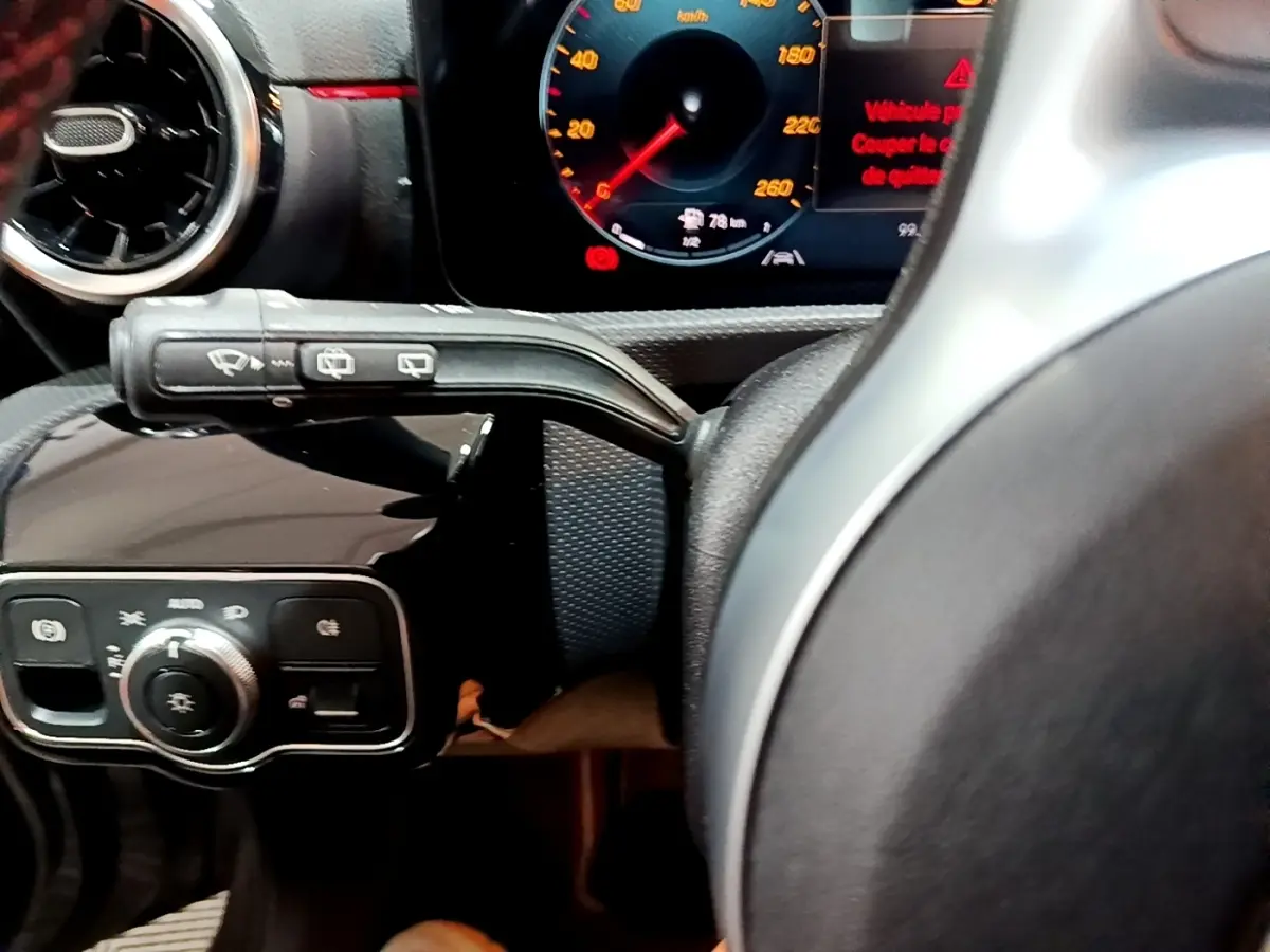 Gros plan sur le volant cuir et alu de la Mercedes Classe A 250 e AMG Line, avec tableau de bord numérique allumé.