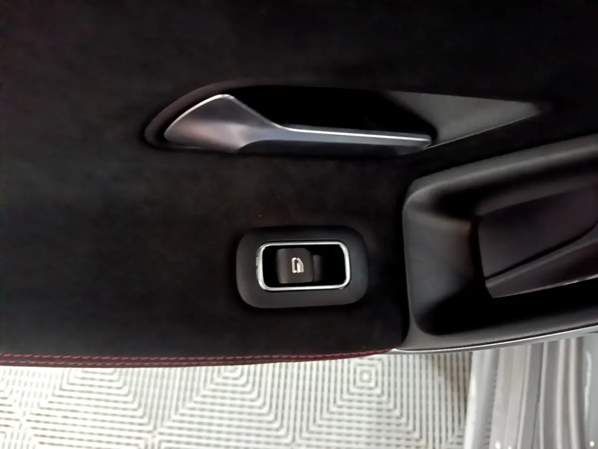 Gros plan sur la poignée intérieure et le bouton de verrouillage de porte, garniture noire avec surpiqûres rouges, Mercedes Classe A.