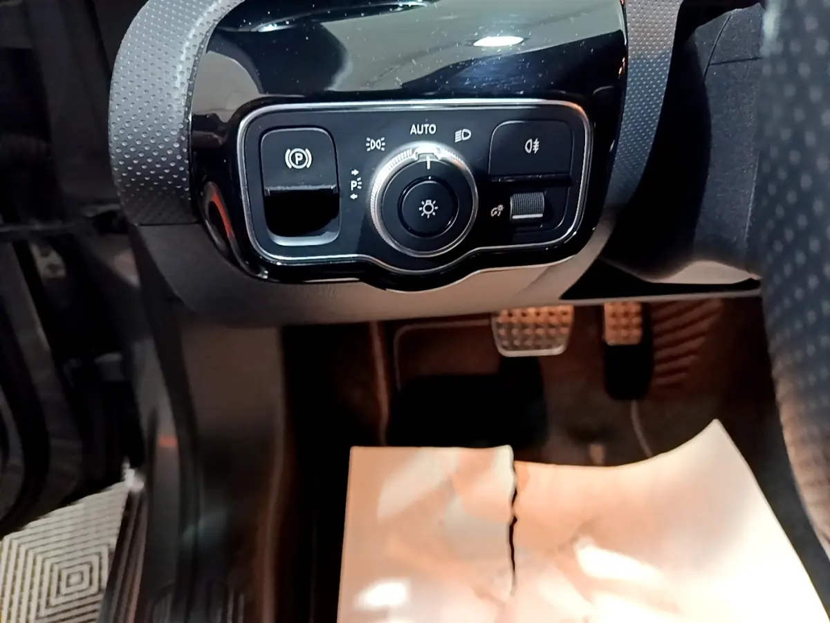 Gros plan sur le panneau de commande des phares et frein à main électrique, intérieur noir du Mercedes Classe A AMG Line.