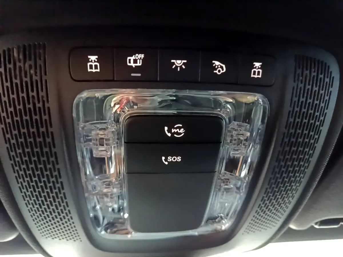 Vue en contre-plongée du panneau de commandes intérieures noires avec boutons SOS et appel d'urgence dans une Mercedes Classe A gris foncé.