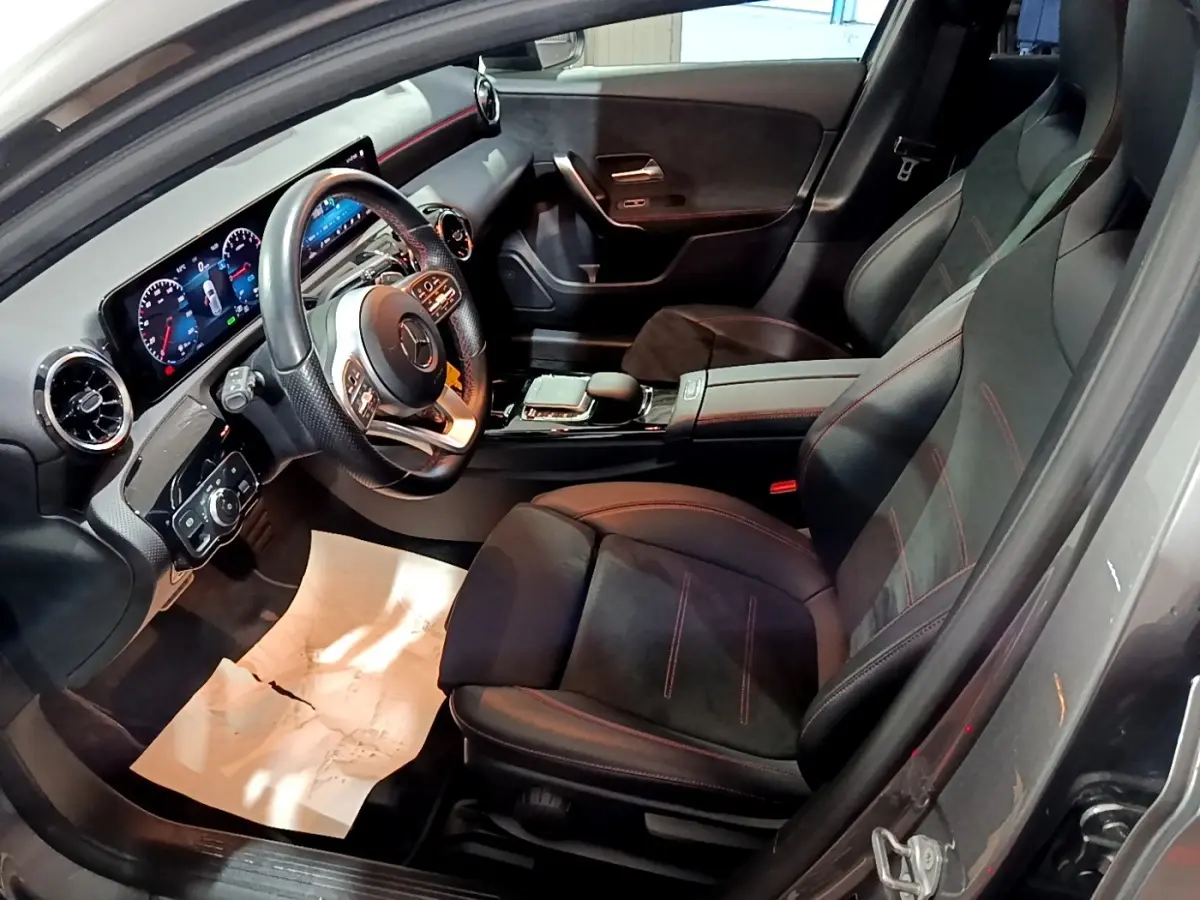 Vue intérieure côté conducteur de la Mercedes Classe A 250 e AMG Line 2021 avec sièges noirs et volant cuir alu multifonctions.